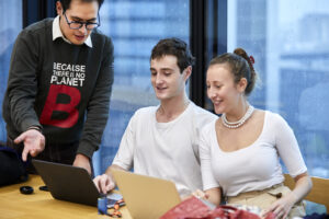 Three students working with a laptop