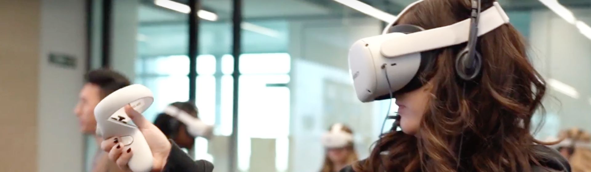 Una estudiante usando gafas de realidad virtual. A student wearing VR goggles, actively engaged in a virtual reality activity.