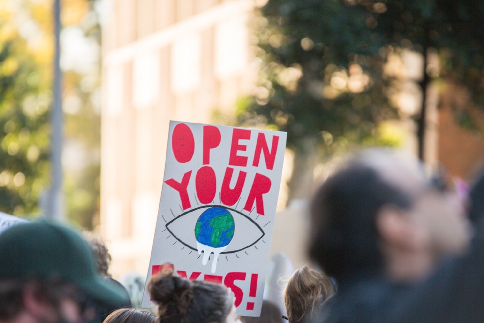 Climate Change protester holds sign saying Open your Eyes at student global warming environmental protest in Melbourne