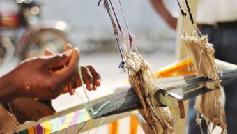 Hands weaving kente cloth